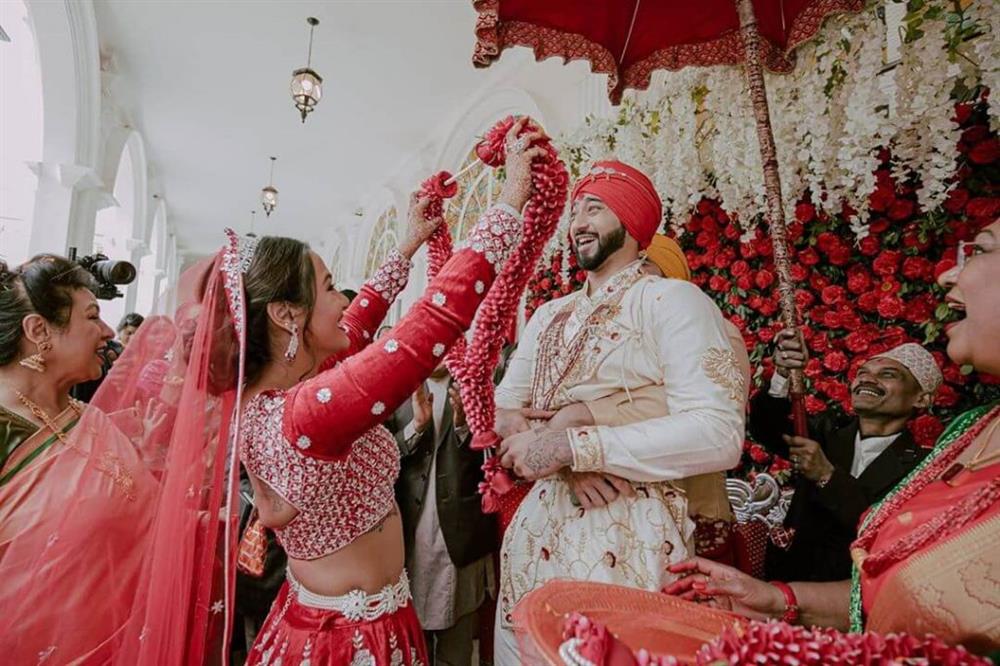 A vibrant and lively pose where the couple exchanges garlands, symbolizing acceptance and unity. 